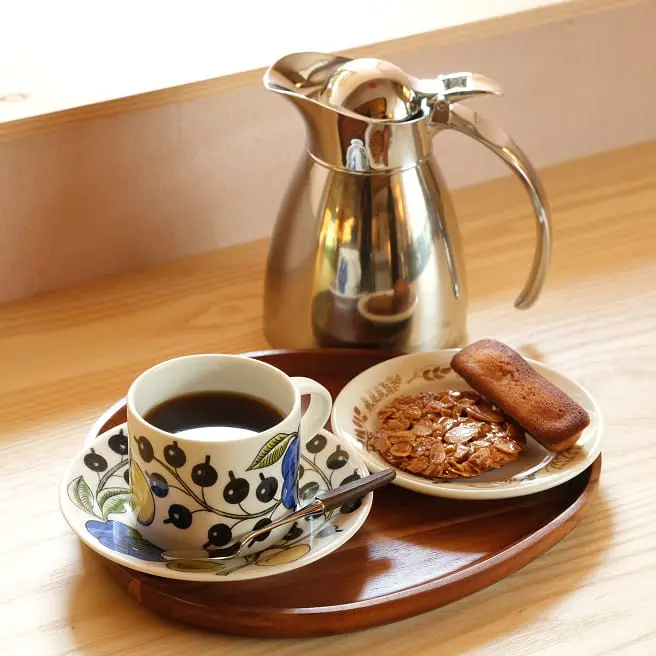 木のカウンターに置かれた、コーヒーと焼き菓子のセットが乗ったトレイ