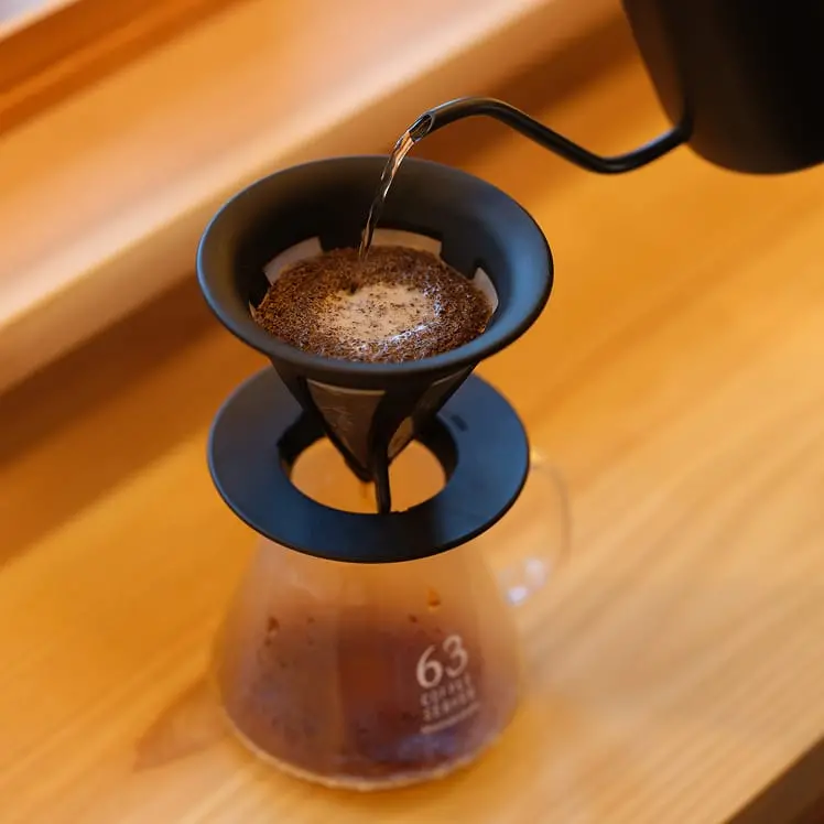 ハンドドリップで丁寧に抽出されるコーヒーが、透明なサーバーに落ちていく様子
