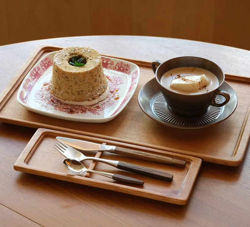 木製トレイに盛りつけられたケーキとドリンクのセットが、カフェテーブルの上に丁寧に並べられている