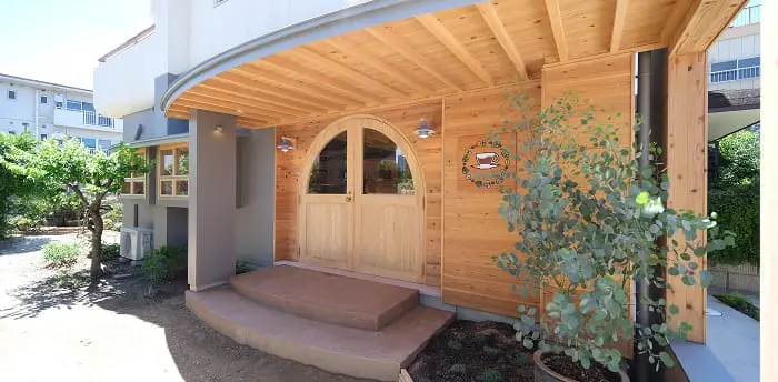 木目調のアーチ型扉が印象的な、温かみのあるデザインのカフェの外観